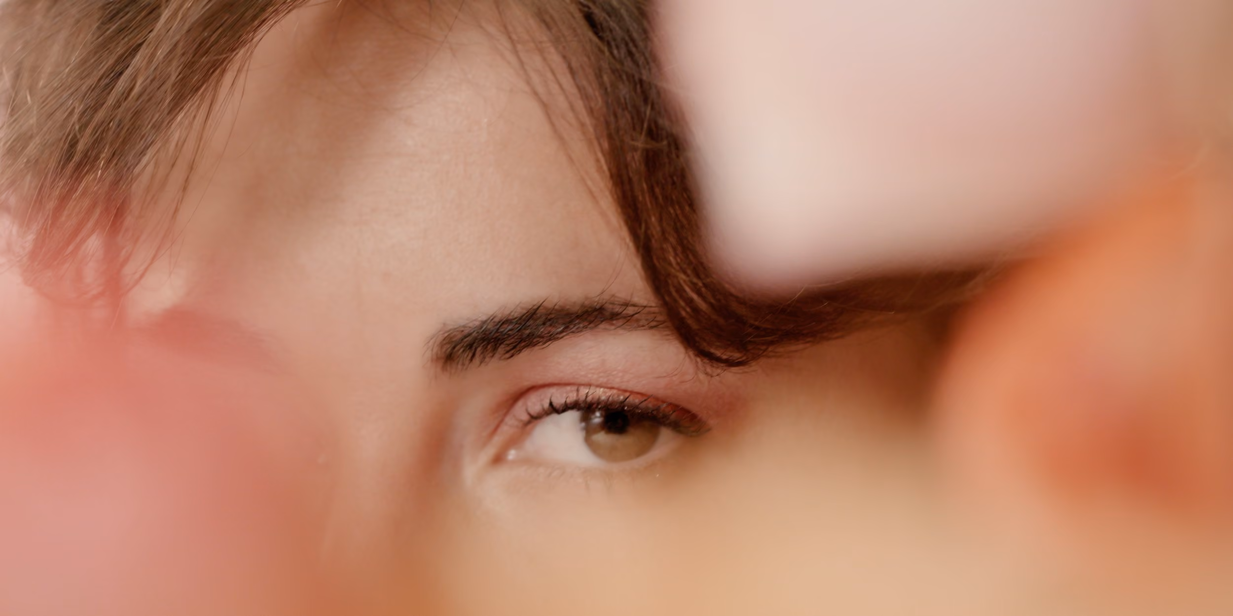 Rostro bajo luz rosada, el pelo cruzando la mirada
