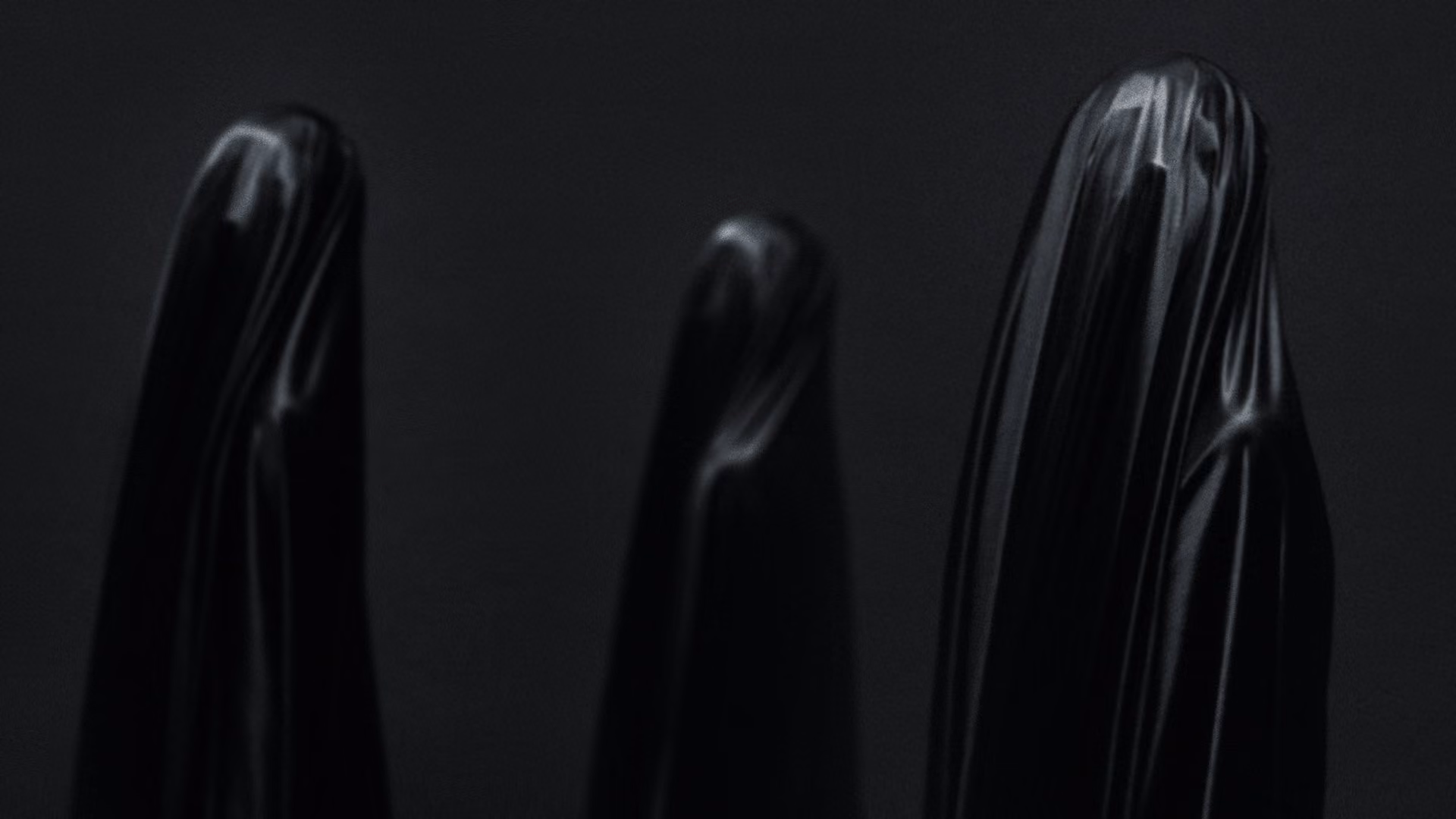Tres formas escultóricas negras y brillantes sobre negro